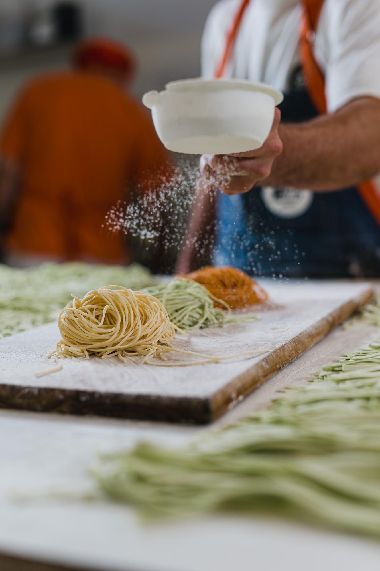 Chef che impasta pasta fresca su tavolo di legno
